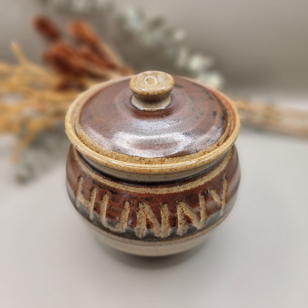 Vintage pottery honey pot with carved lettering reading “HUNNY”