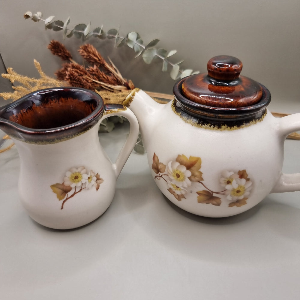 Stoneware teapot set with white floral design, includes teapot, creamer and sugar bowl.