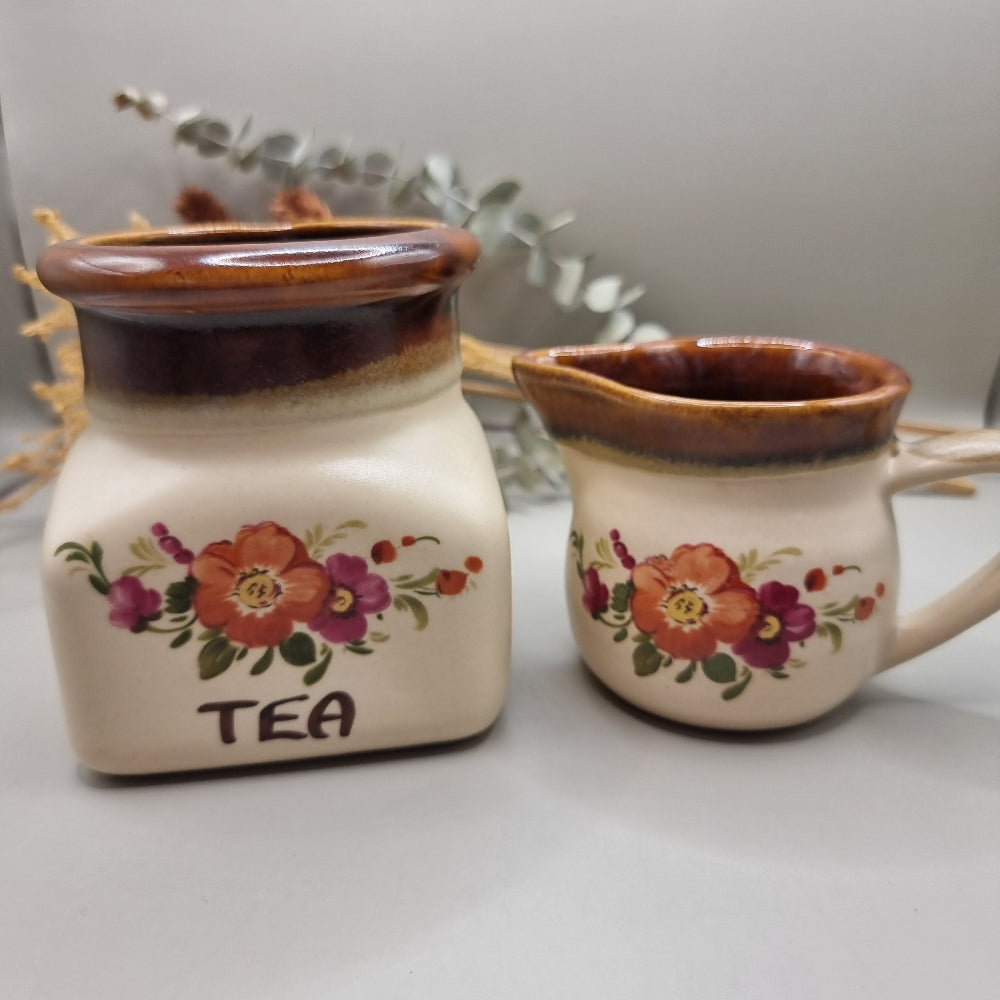 Floral ceramic tea jar and creamer jug with brown glaze and hand-painted flowers.