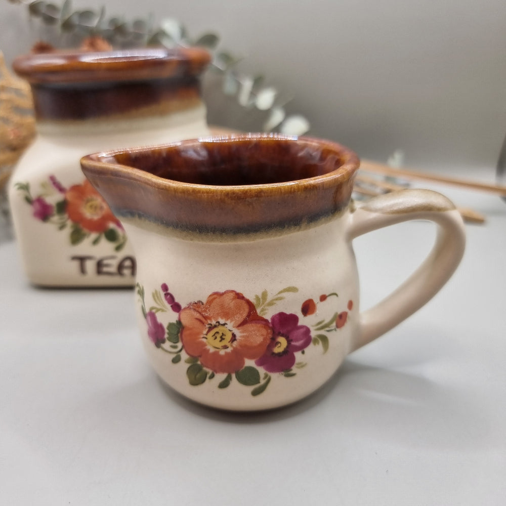 Floral ceramic tea jar and creamer jug with brown glaze and hand-painted flowers.