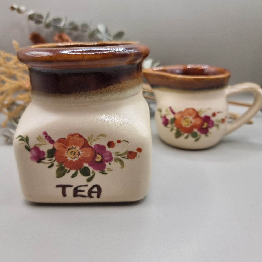 Floral ceramic tea jar and creamer jug with brown glaze and hand-painted flowers.