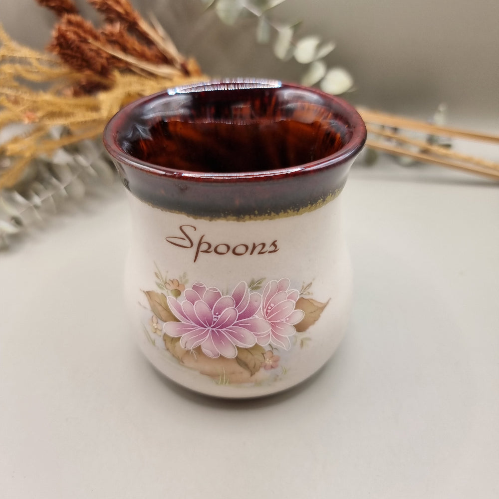 Ceramic spoon holder with pink floral design and brown glazed rim.
