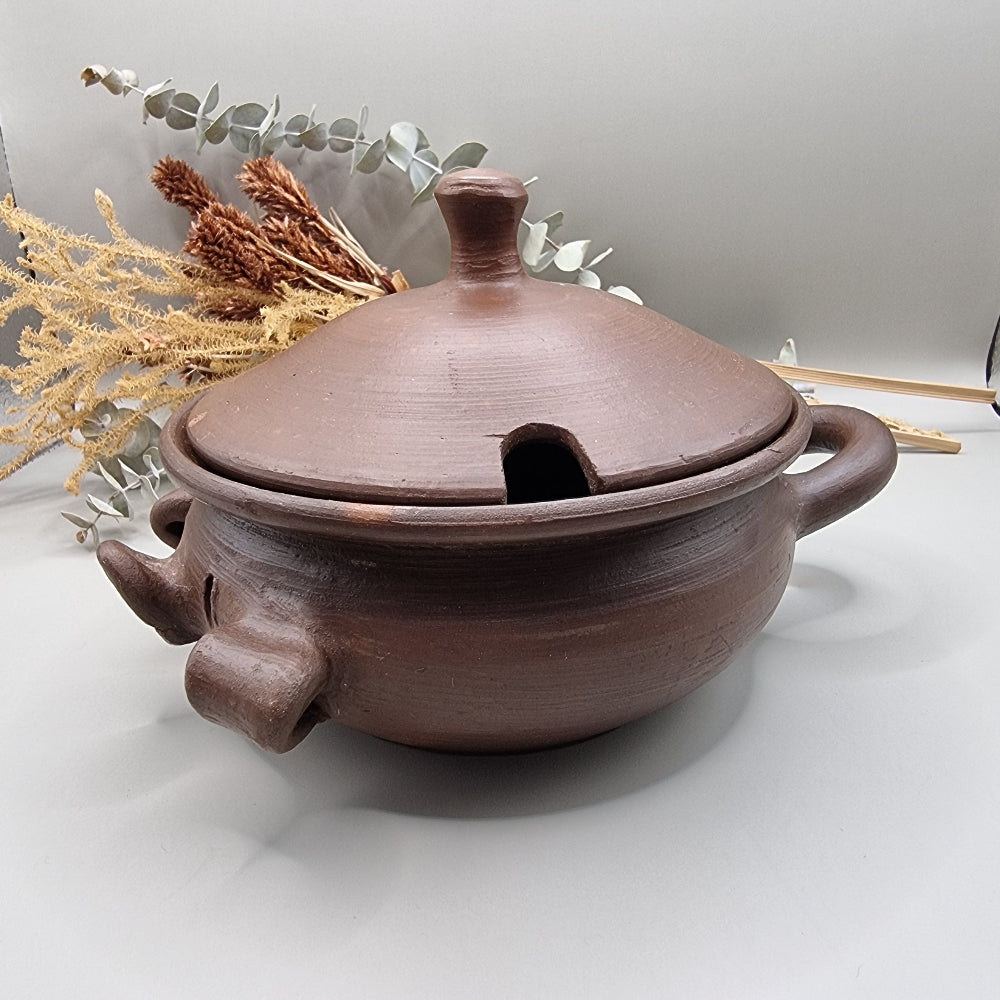 Handmade terracotta pig bowl with lid, ideal for salt or sugar storage in a rustic kitchen.