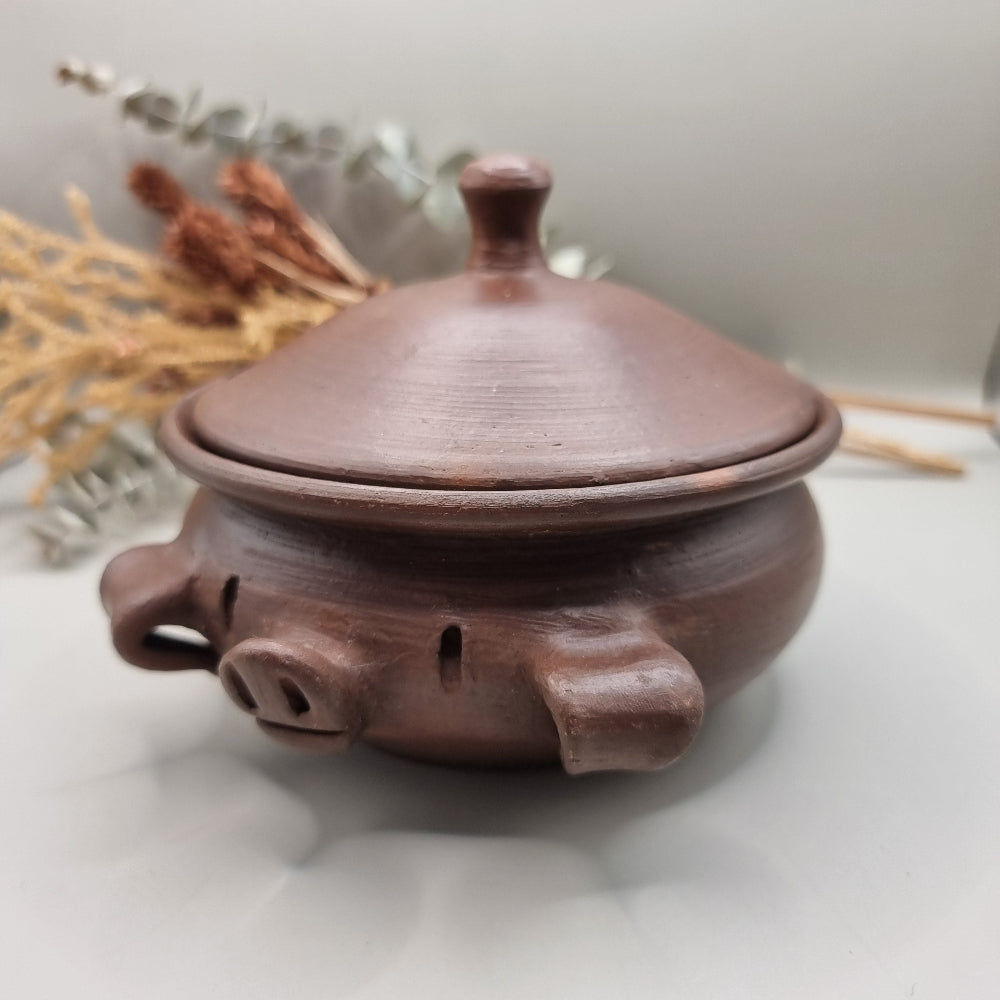 Handmade terracotta pig bowl with lid, ideal for salt or sugar storage in a rustic kitchen.