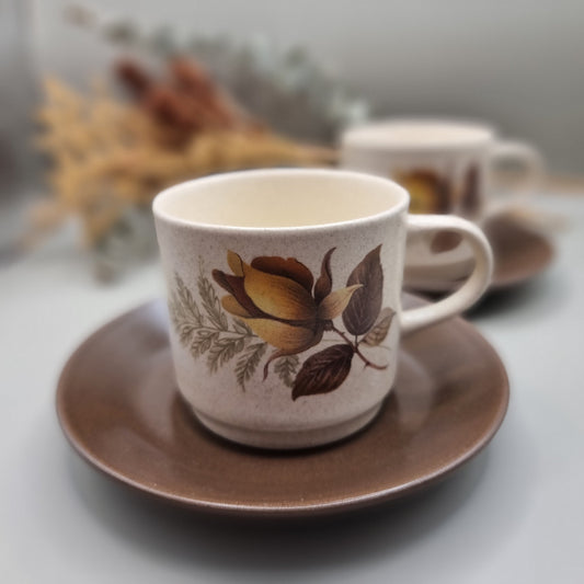 Australian-made retro stoneware cups with golden rose design and brown saucers, set of two.