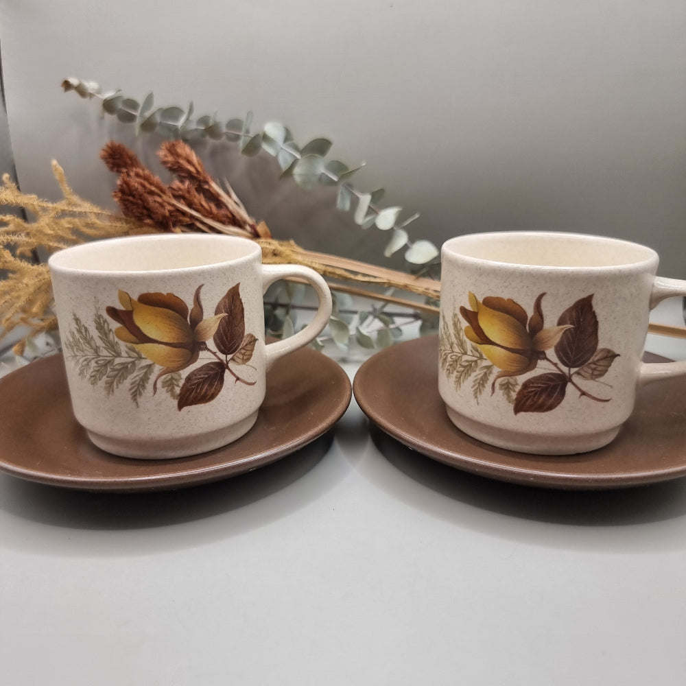 Australian-made retro stoneware cups with golden rose design and brown saucers, set of two.