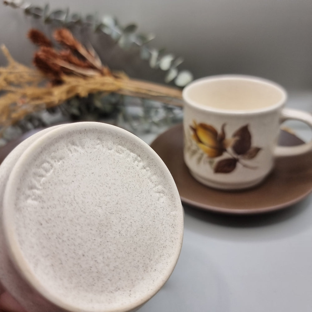 Australian-made retro stoneware cups with golden rose design and brown saucers, set of two.