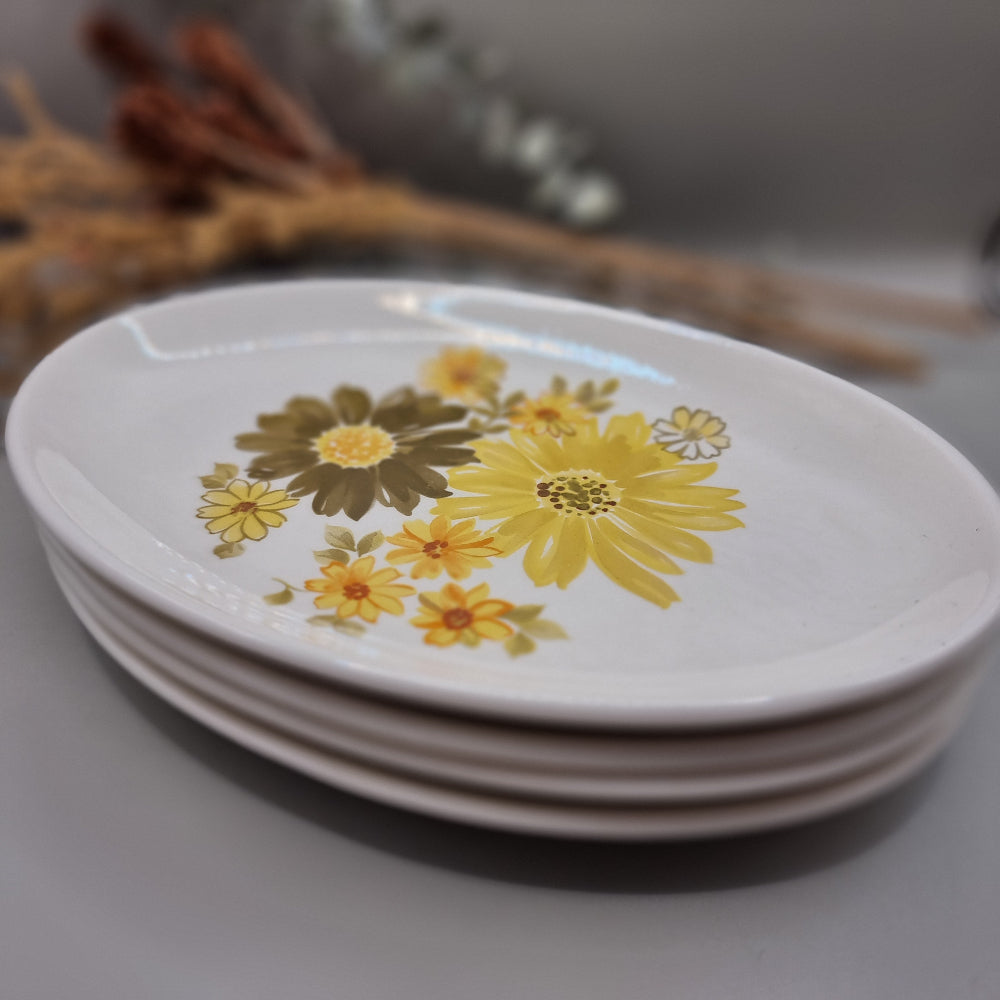 Set of four Crown Lynn Topaz plates with bold yellow and orange flowers.