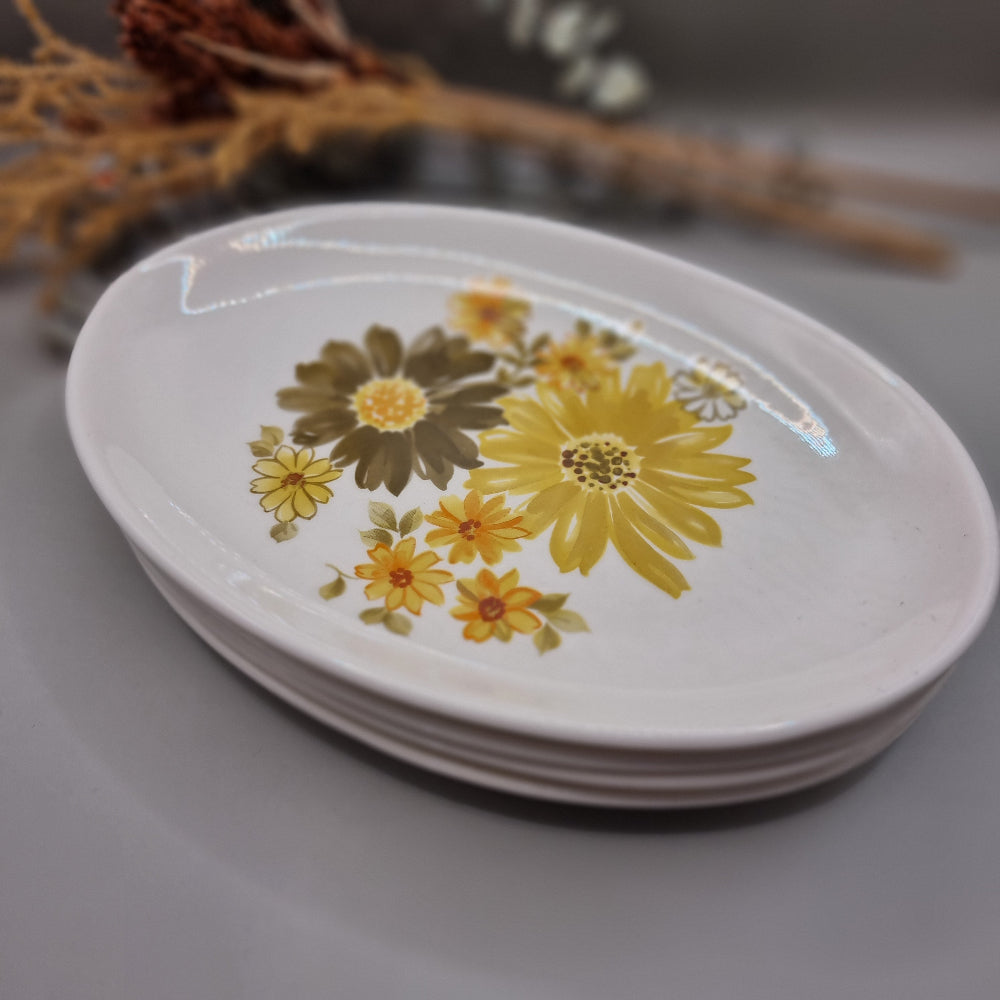 Set of four Crown Lynn Topaz plates with bold yellow and orange flowers.