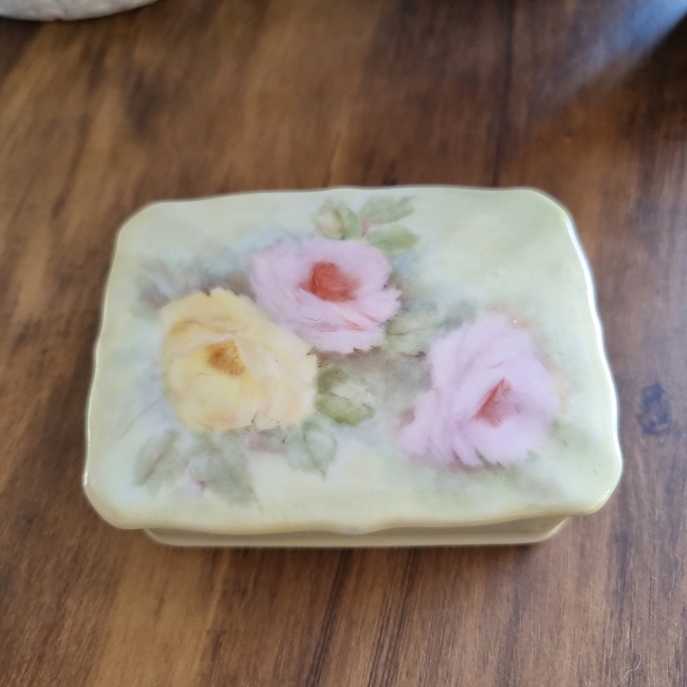 Porcelain trinket box with hand-painted pastel roses and scalloped edge lid.