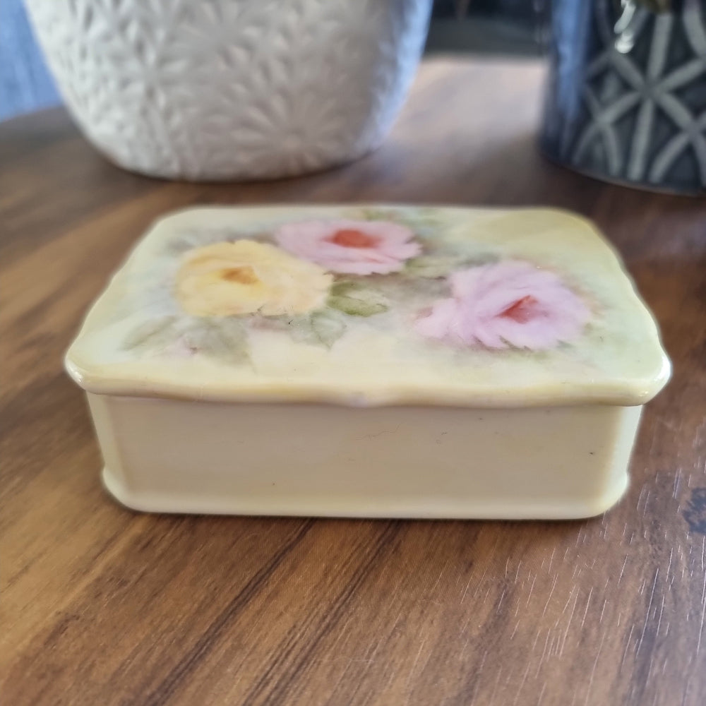 Porcelain trinket box with hand-painted pastel roses and scalloped edge lid.