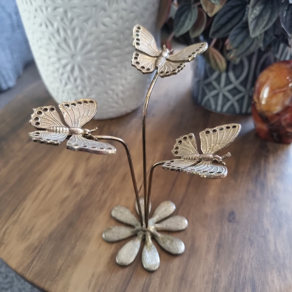 Gold butterfly earring holder with three butterflies on stems and daisy-style base.