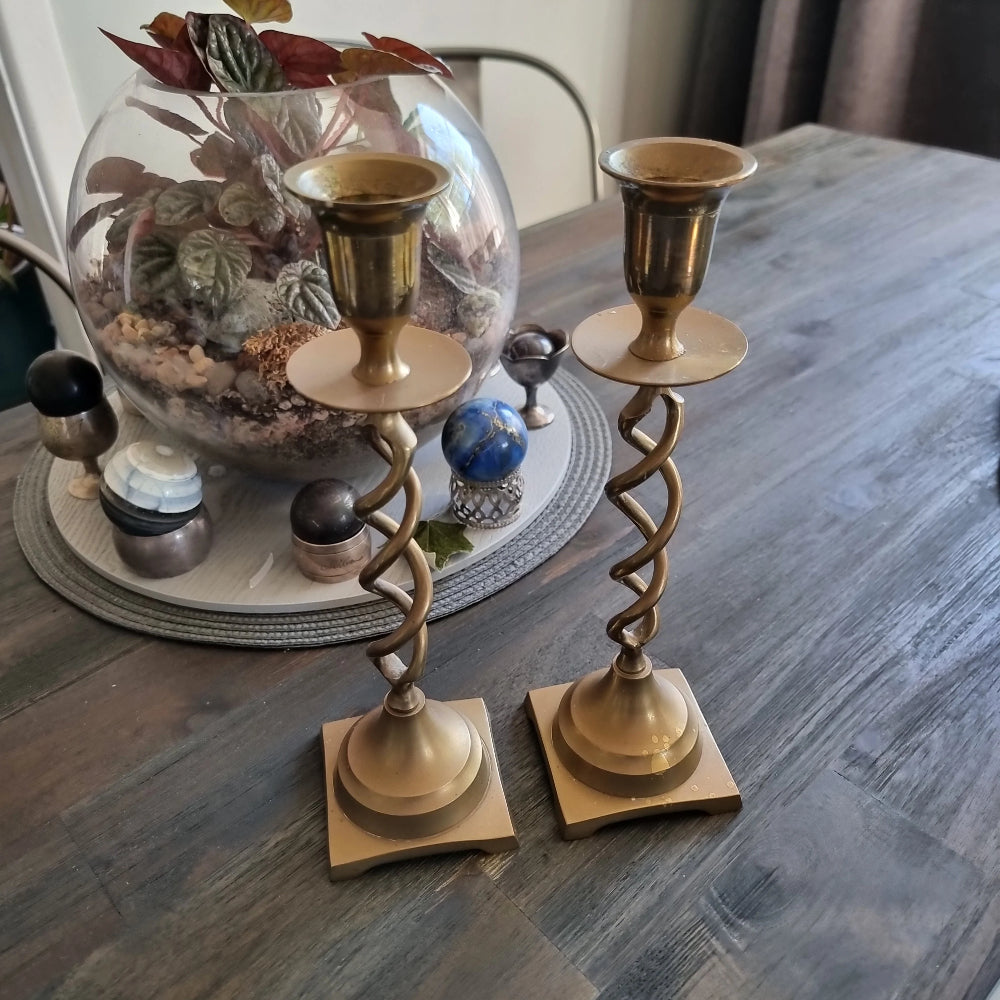 Pair of vintage brass barley twist candlesticks with square bases on a wooden table