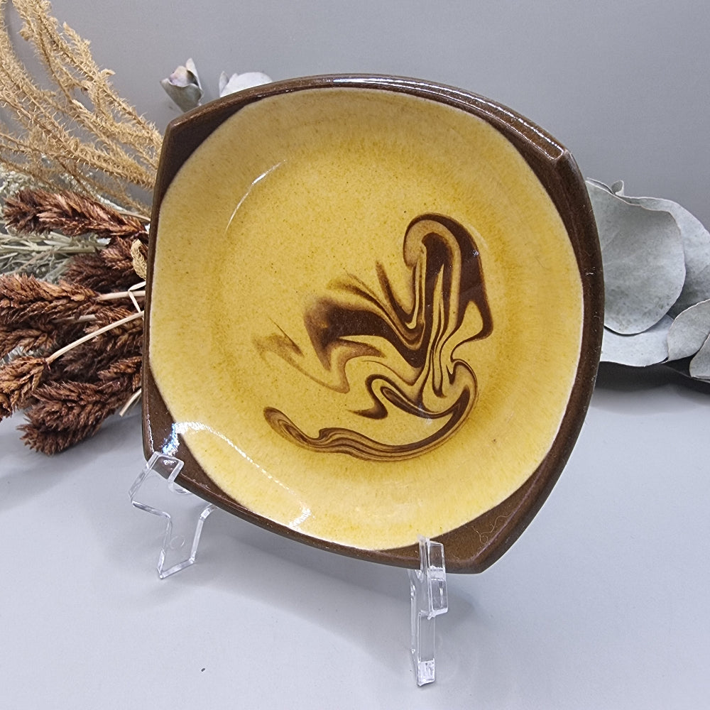 Retro mustard and brown swirl ceramic dish with square edges.