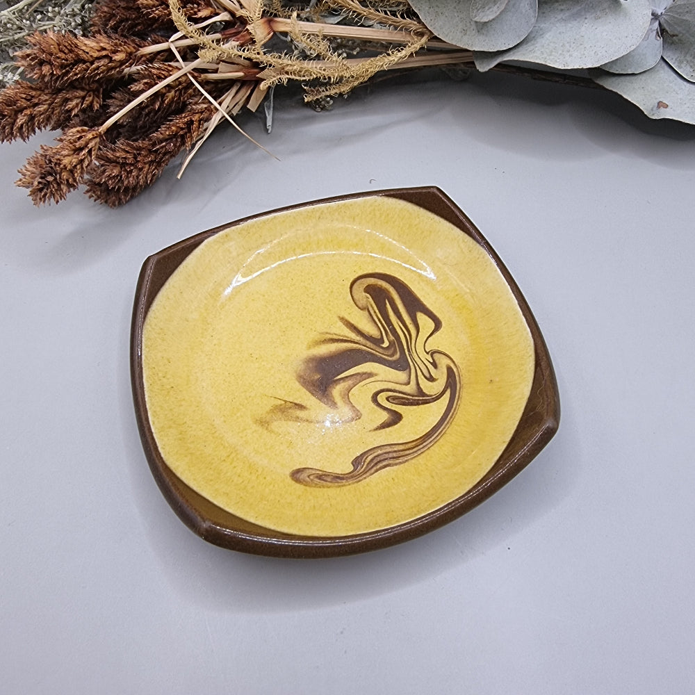 Retro mustard and brown swirl ceramic dish with square edges.