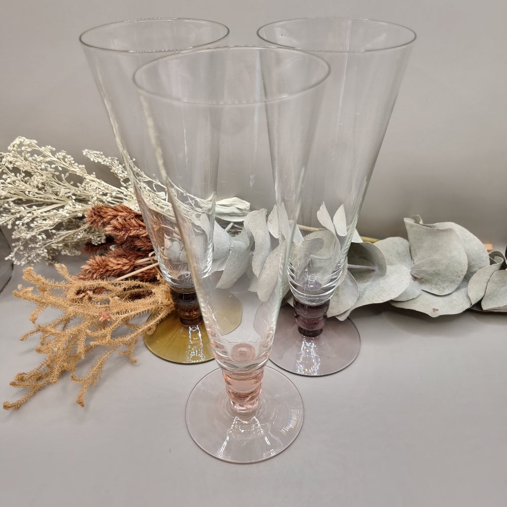 Set of three champagne flutes with pink, amber, and plum coloured bases