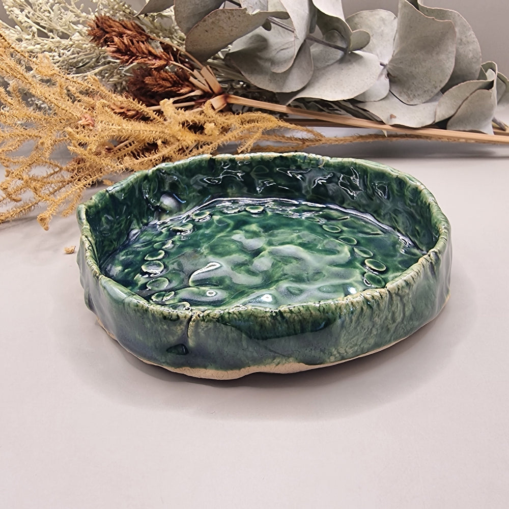 Handmade green ceramic dish with rippled glossy surface and organic edges