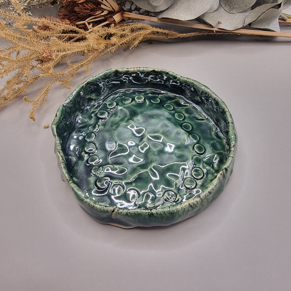 Handmade green ceramic dish with rippled glossy surface and organic edges