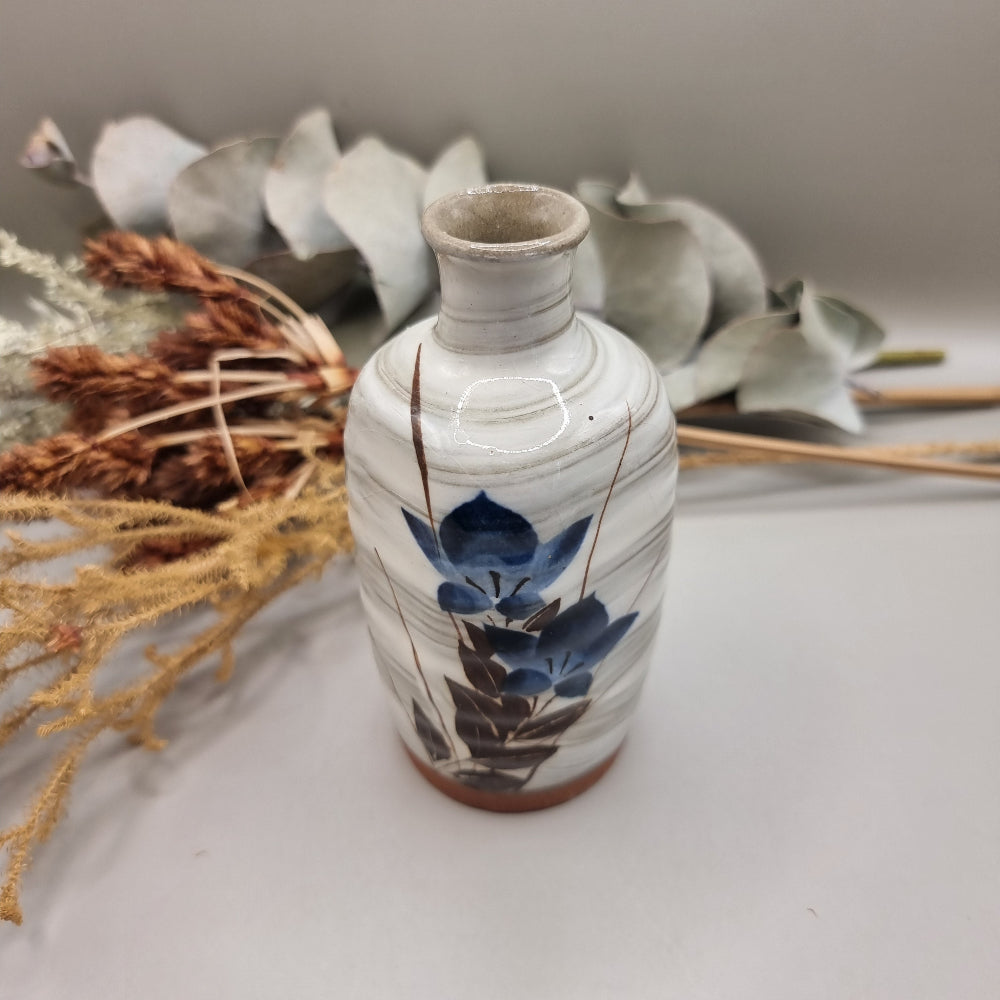 Vintage hand-painted ceramic bud vase with blue floral design and terracotta base.