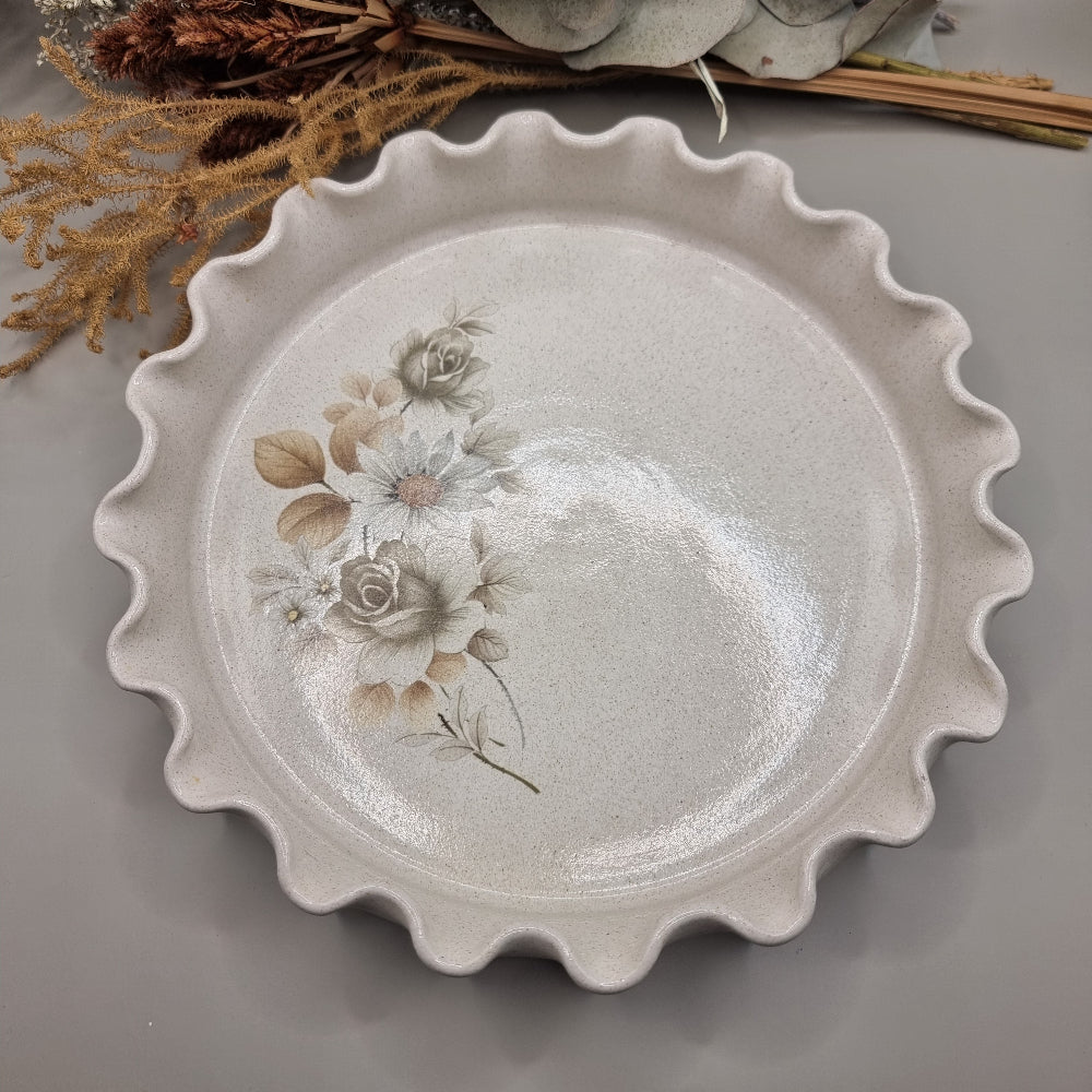 Vintage flan dish with floral pattern and wavy scalloped edge.