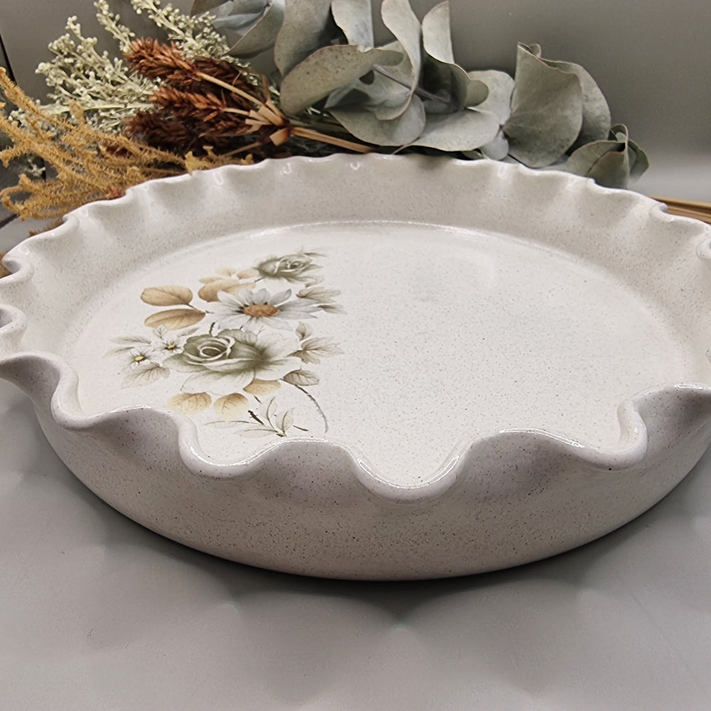 Vintage flan dish with floral pattern and wavy scalloped edge.