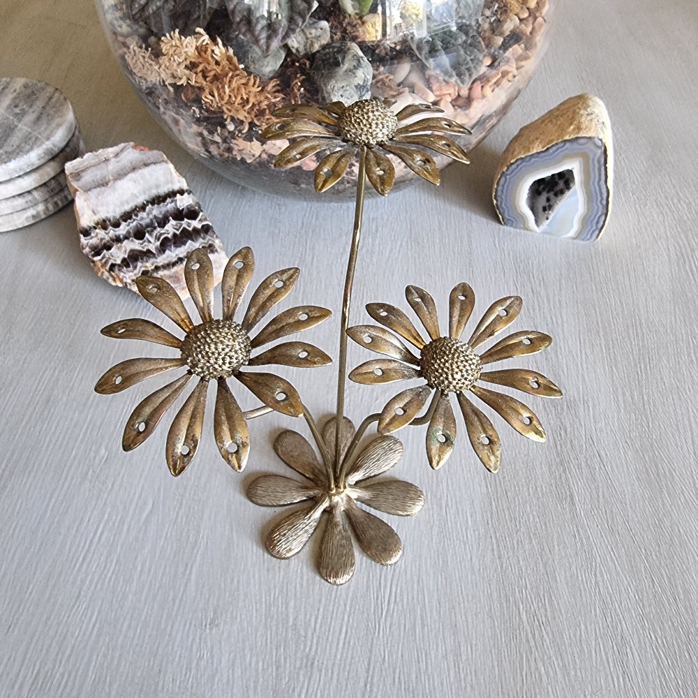 Vintage brass earring holder with three daisy flowers and petal holes for displaying earrings.