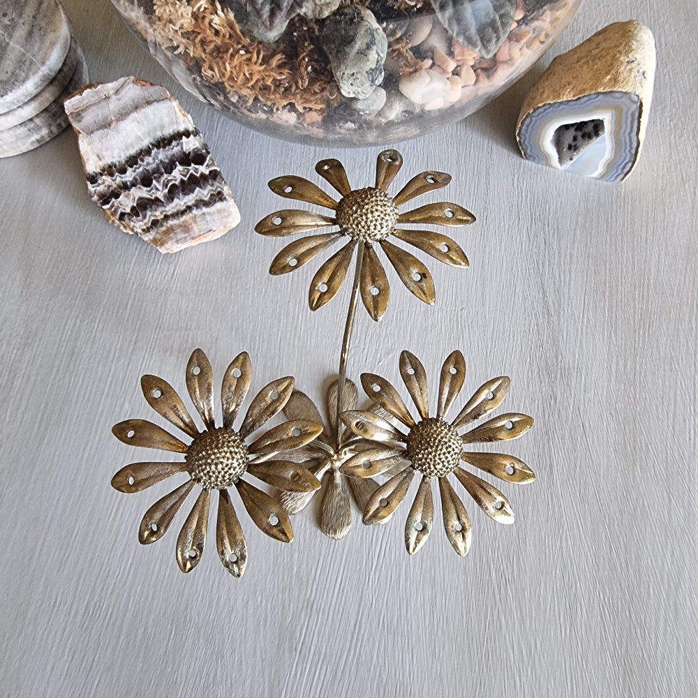 Vintage brass earring holder with three daisy flowers and petal holes for displaying earrings.