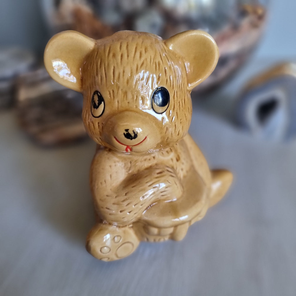Vintage ceramic bear-shaped honey pot with cartoon eyes and paw prints.