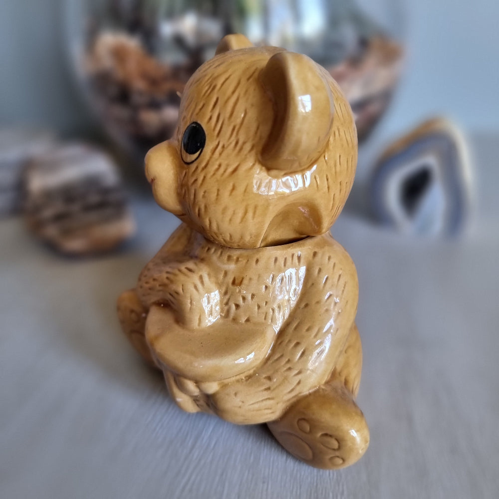 Vintage ceramic bear-shaped honey pot with cartoon eyes and paw prints.