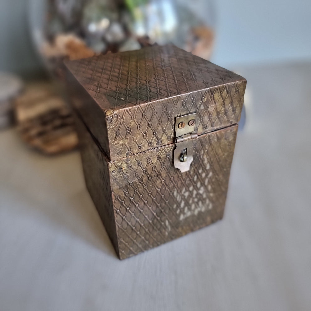 Square wooden box with diamond brass embossing and hinged lid.