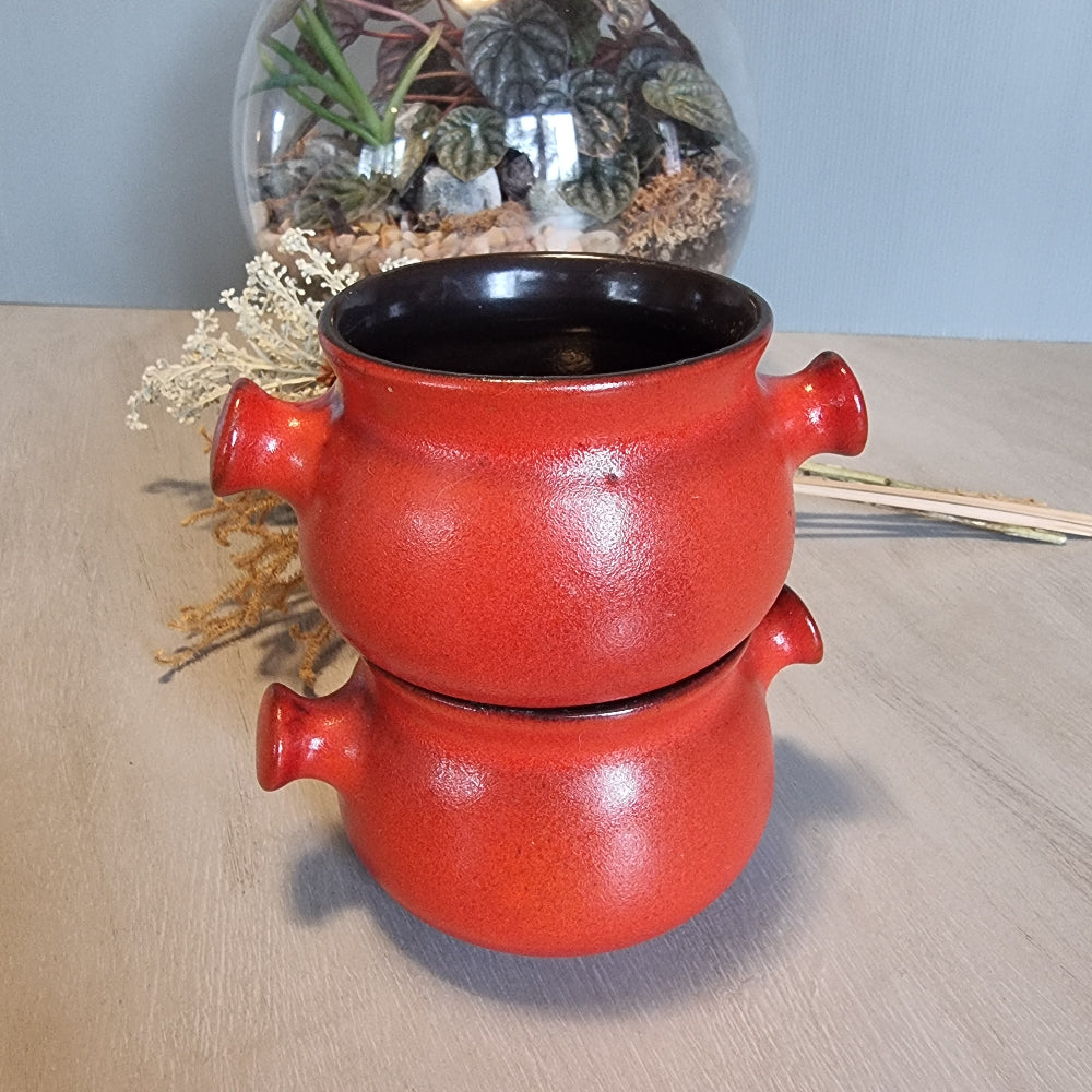 Pair of vintage red ceramic soup bowls with double handles and black interior.