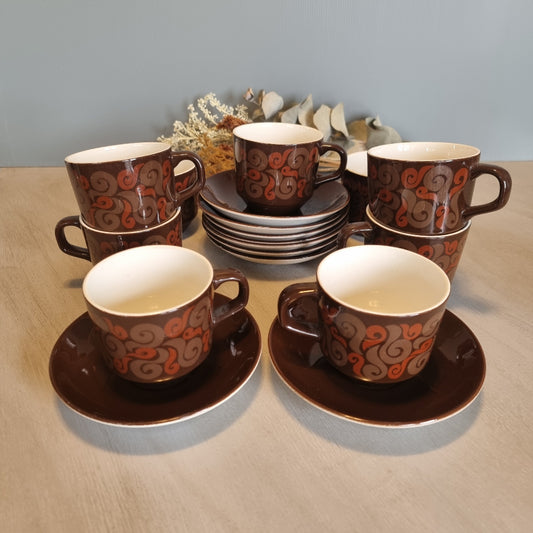 Set of 9 Crown Lynn cups and saucers with brown glaze and orange swirl design.