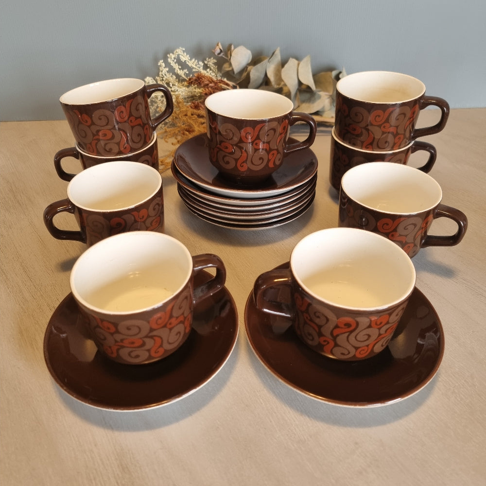 Set of 9 Crown Lynn cups and saucers with brown glaze and orange swirl design.