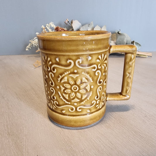 Crown Lynn embossed floral mug in caramel glaze with raised scroll and flower design.
