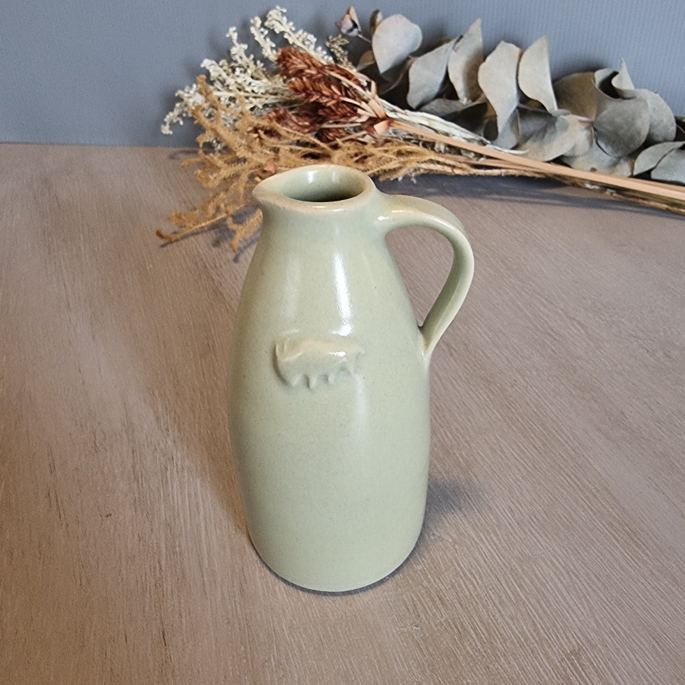 Green ceramic jug with embossed buffalo motif, rustic farmhouse kitchen collectible.