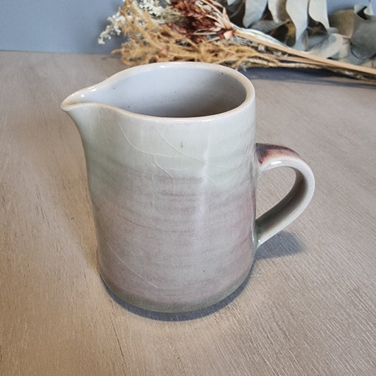 Handmade ceramic jug with blush and cream glaze, rustic and functional pottery piece.