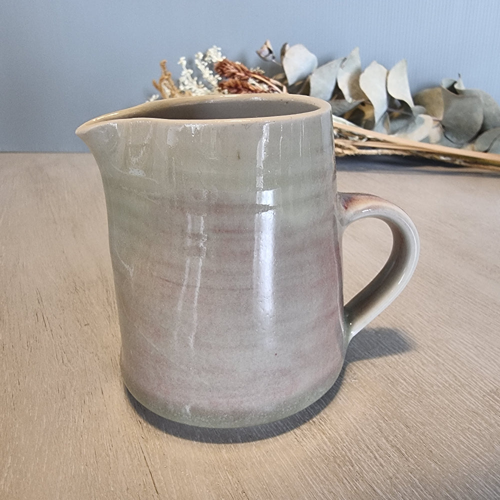 Handmade ceramic jug with blush and cream glaze, rustic and functional pottery piece.