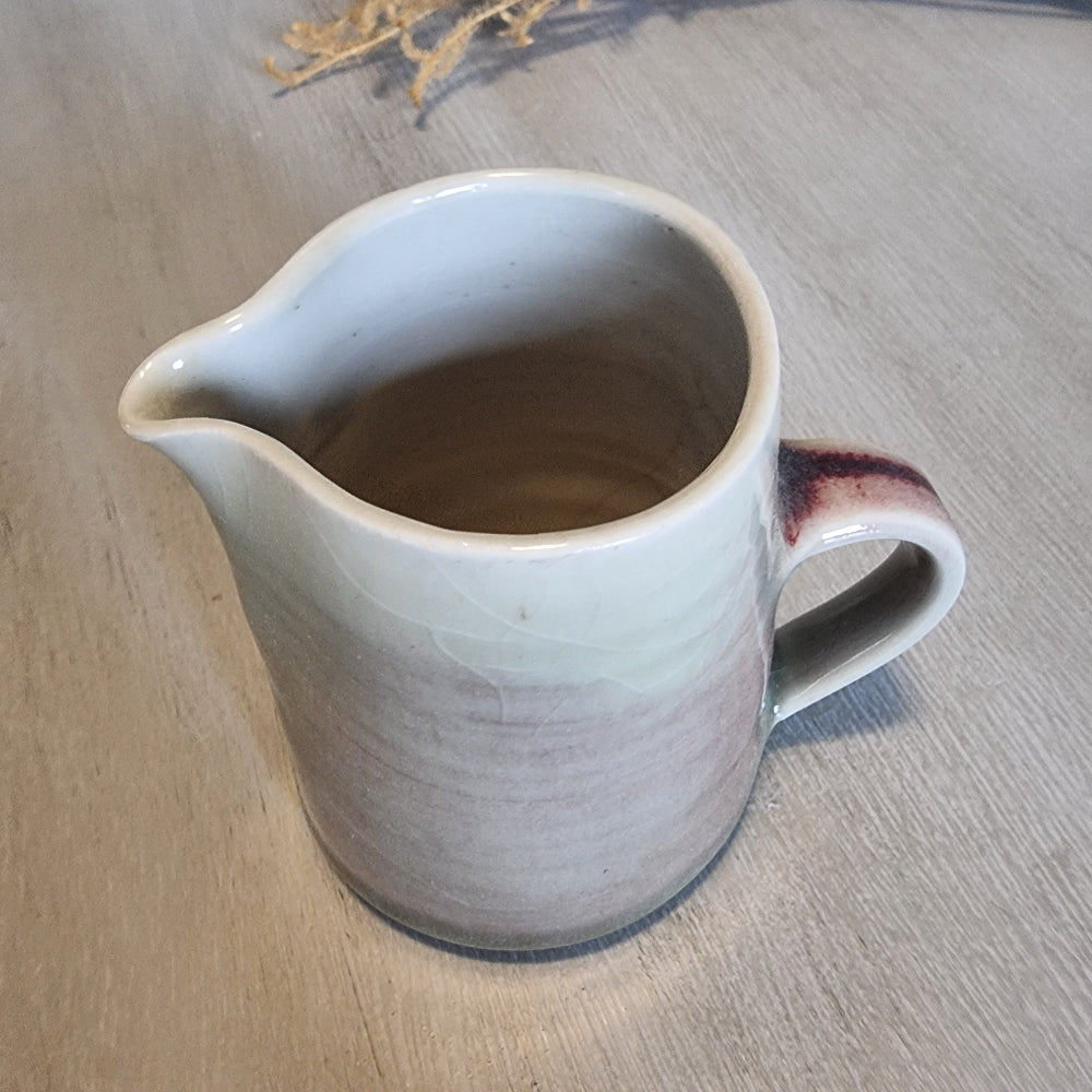 Handmade ceramic jug with blush and cream glaze, rustic and functional pottery piece.