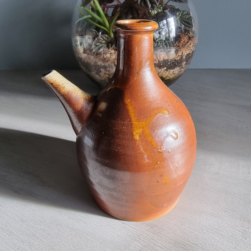 Vintage brown pottery jug with side spout and natural glaze finish.