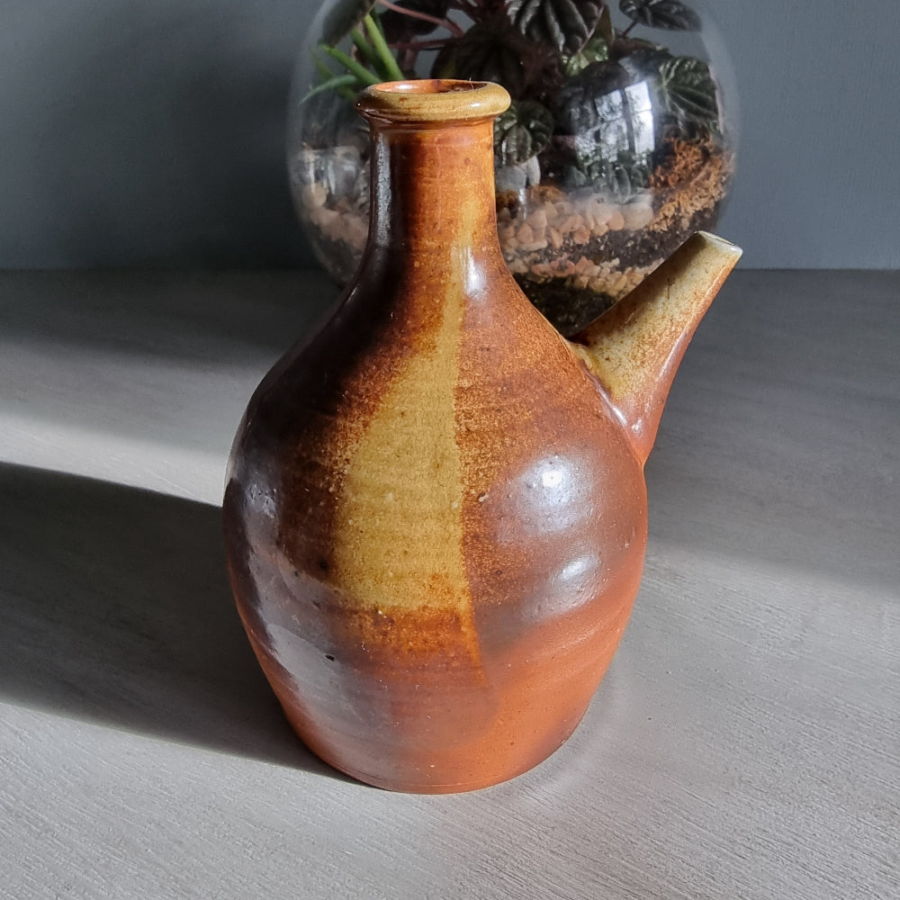 Vintage brown pottery jug with side spout and natural glaze finish.