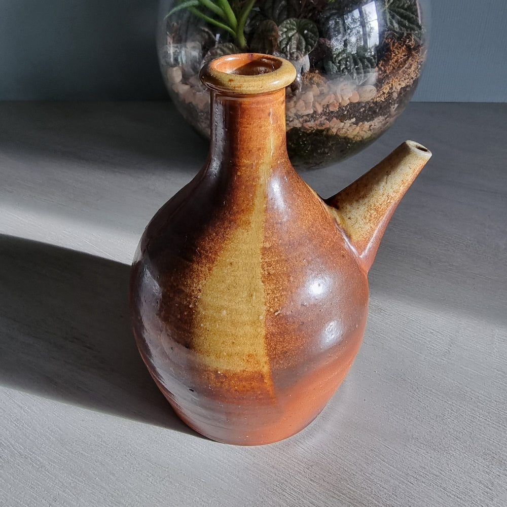 Vintage brown pottery jug with side spout and natural glaze finish.
