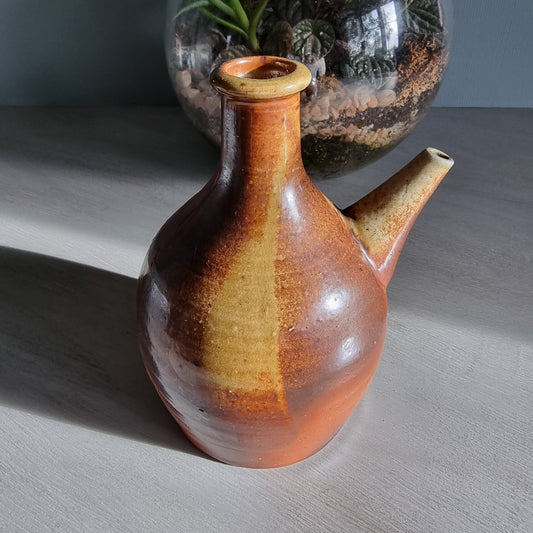 Vintage brown pottery jug with side spout and natural glaze finish.