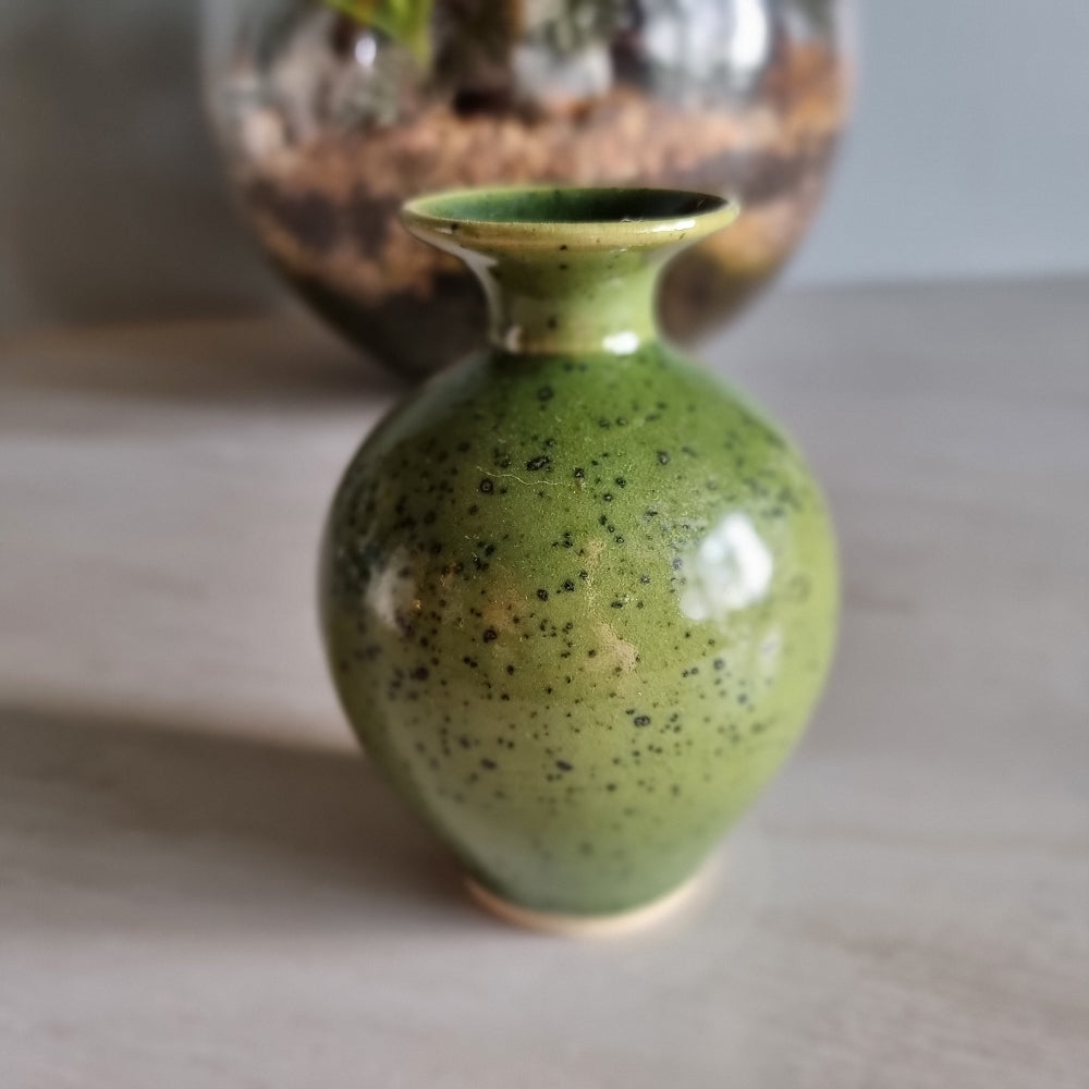 Small green speckled pottery vase with glossy glaze.