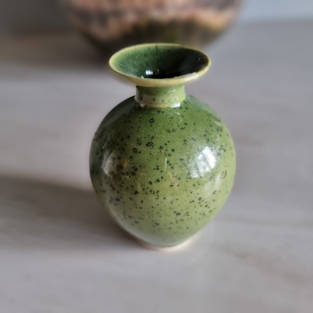 Small green speckled pottery vase with glossy glaze.