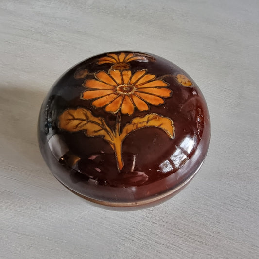 Brown ceramic trinket dish with orange floral design and matching lid.