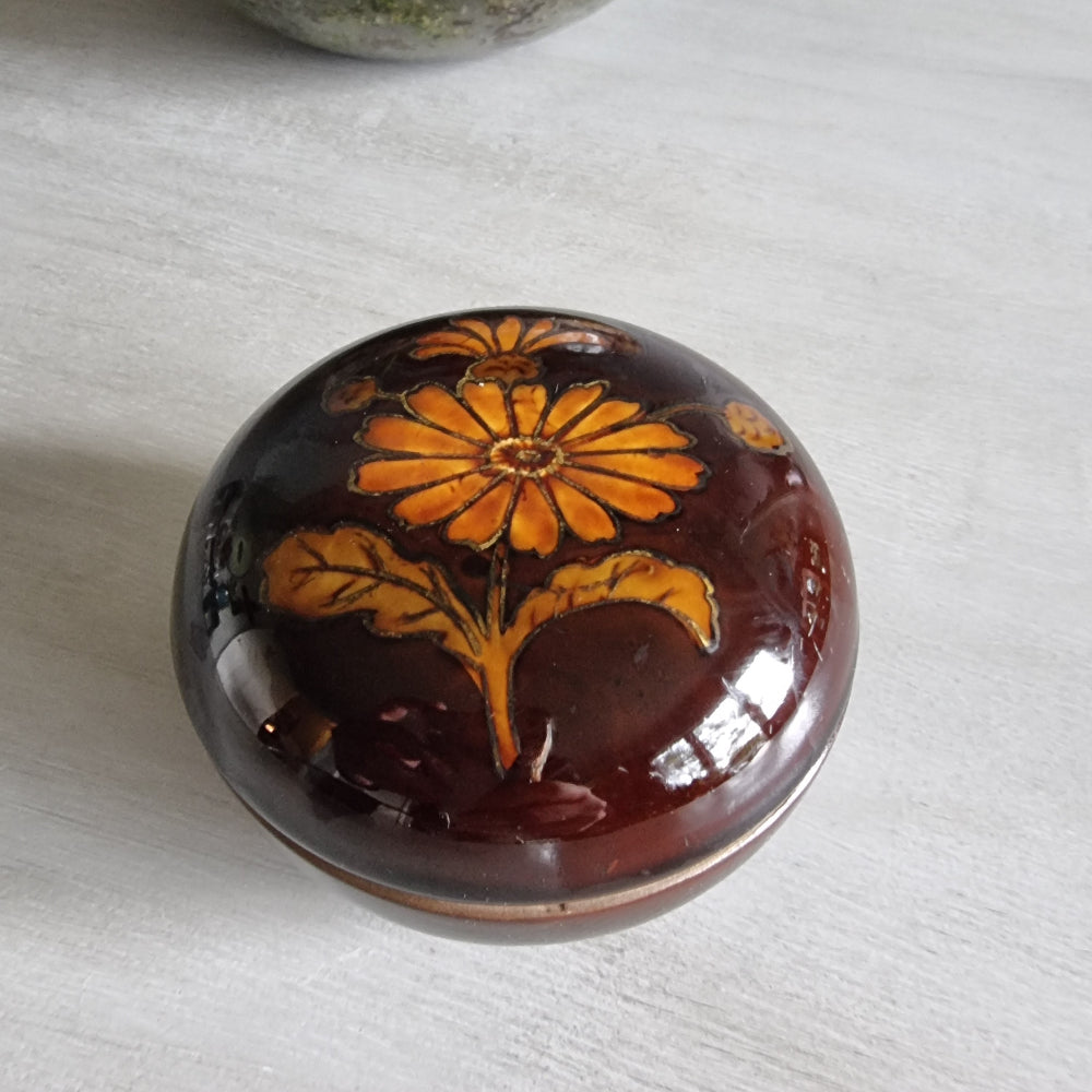 Brown ceramic trinket dish with orange floral design and matching lid.
