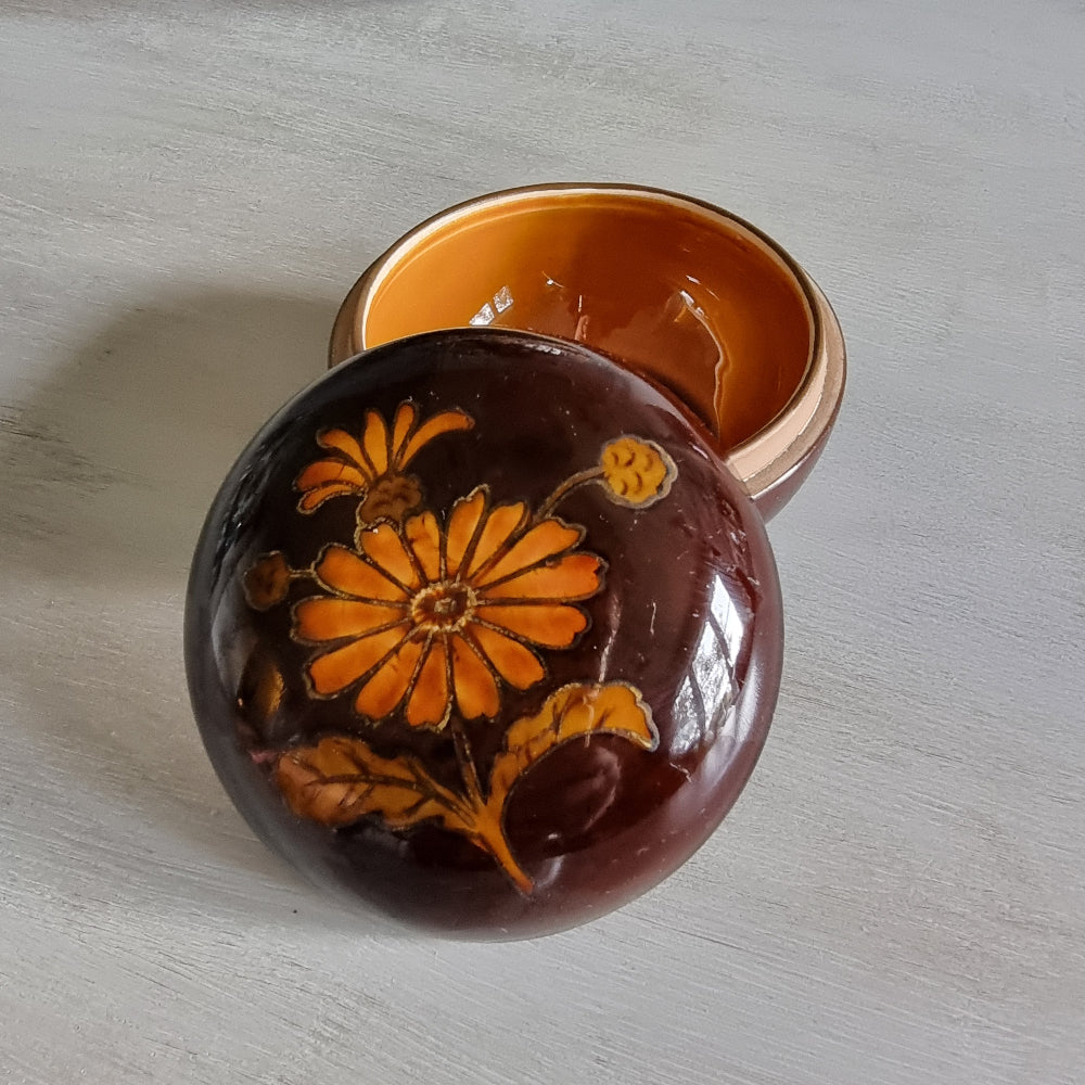 Brown ceramic trinket dish with orange floral design and matching lid.