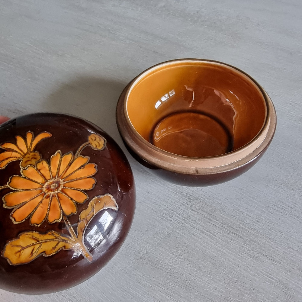 Brown ceramic trinket dish with orange floral design and matching lid.