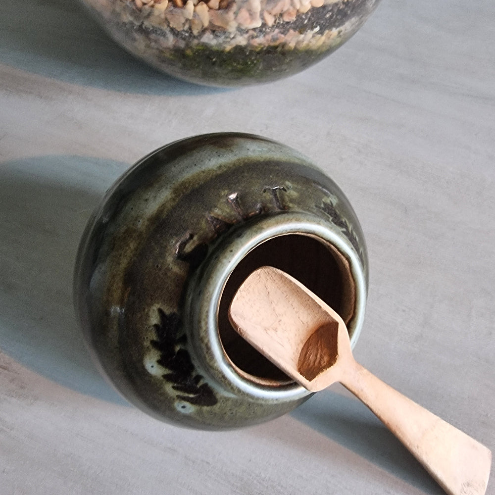 Vintage green glazed pottery salt jar with wooden scoop.