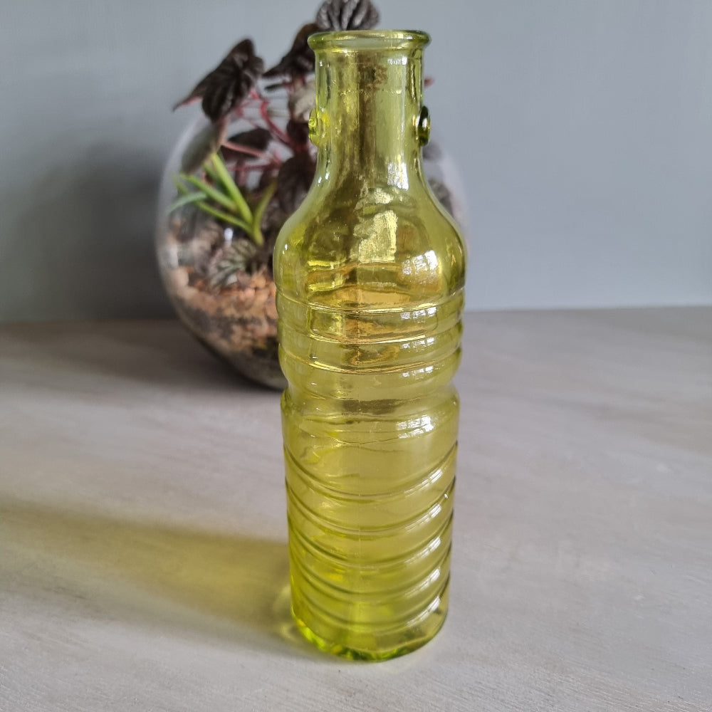 Vintage yellow-green ribbed glass bottle with small handles and retro charm.